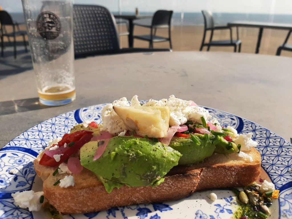 Avocado on Sourdough, topped with crumbled feta, fresh chili, pine nuts, pomegranate seeds, and a drizzle of pesto dressing.