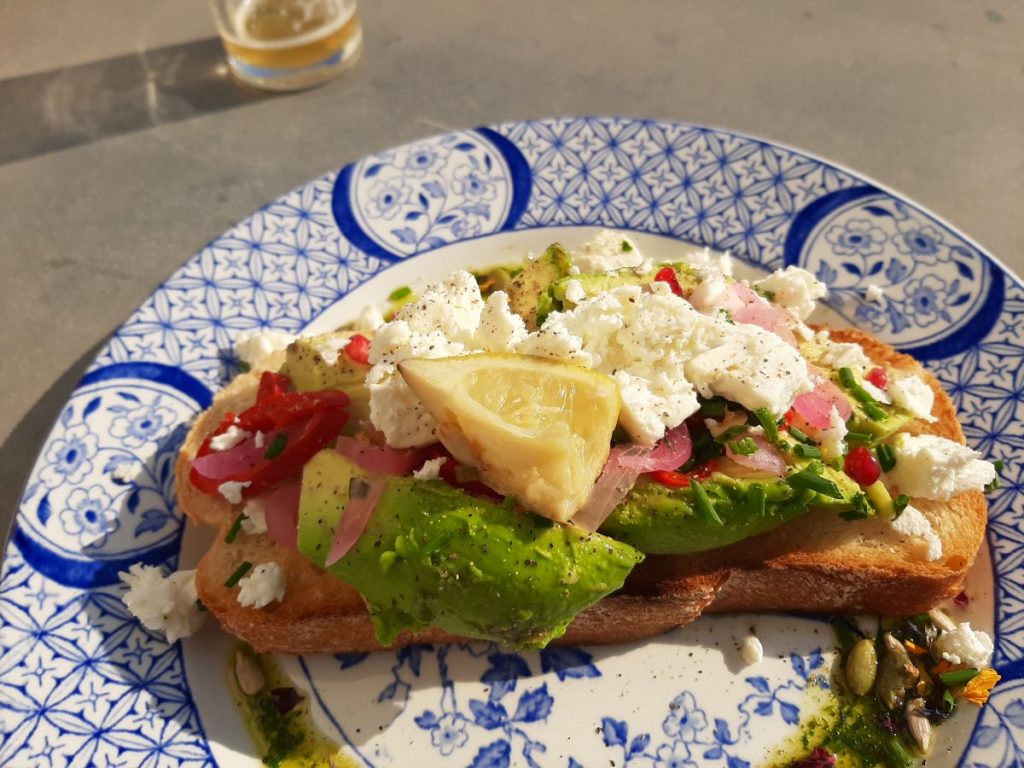 Avocado on Sourdough, topped with crumbled feta, fresh chili, pine nuts, pomegranate seeds, and a drizzle of pesto dressing.