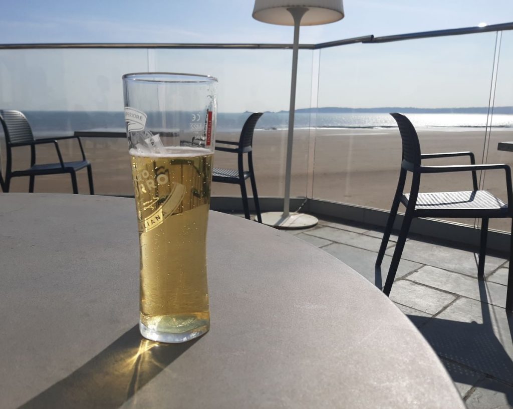 A cold glass of Peroni overlooking Swansea Beach and Mumbles Pier in the distance.