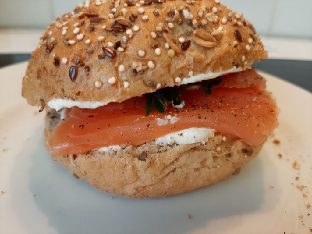 Agos o eog mwg ffres gyda chaws meddal, cennin, pupur du wedi'i falu, a gwasgiad o lemwn. Rholyn Grawn Hynafol yn llawn hadau.