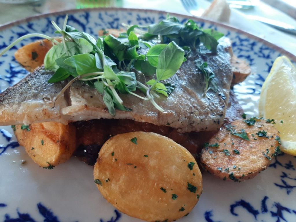 The Provençal Fillet - grilled seabass with Cobi’s tomato sauce, whole green olives, crispy potatoes, and lemon at the Gin & Juice Mumbles Swansea