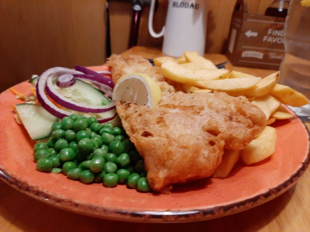 Pysgodyn a Sglodion – Ffiled ffres o benfras mewn cytew crensiog cartref, wedi'i weini gyda sglodion, pys, a lletem o lemwn yn 'The New Tredegar Arms Cwmtwrch'